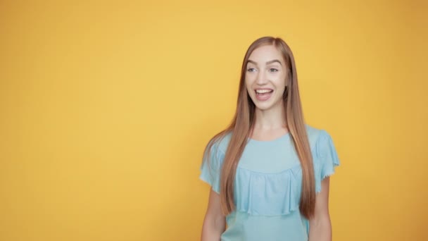 girl brunette in blue t-shirt over isolated orange background shows emotions - Metraje, vídeo
