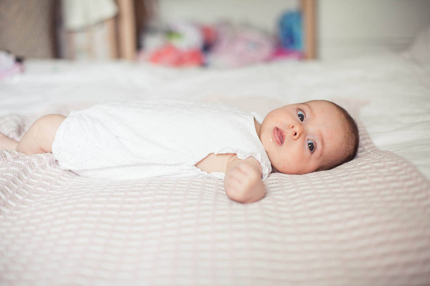 Маленькая симпатичная девочка 3 месяцев лежит на кровати. Детка. Детская спальня
. - Фото, изображение