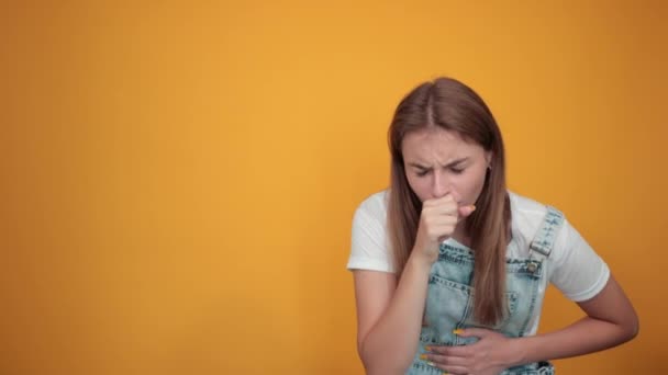 Young woman wearing white t-shirt, over orange background shows emotions - Footage, Video
