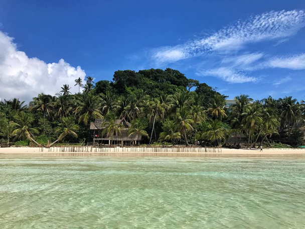 Чистый океан, пляж с белым песком и дом на острове в окружении зеленых пальм на острове Боракай, Филиппины
 - Фото, изображение