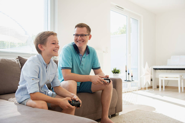 Gelukkige jonge vader en zijn zoon spelen computerspelletjes met con - Foto, afbeelding