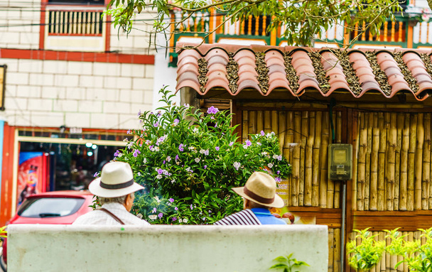 Mensen van Colombia, groep van oude man zittend op bankje in de kleurrijke straten van Filandia Village - Foto, afbeelding