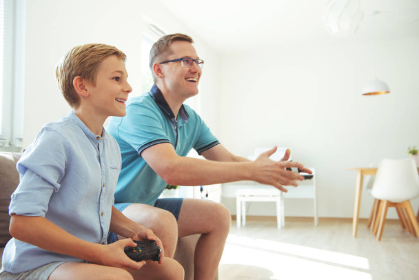 Happy young father and  his son playing computer games  with con - Photo, Image