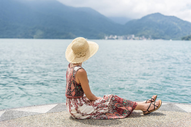 woman with hat sit at a pier - Foto, Imagen
