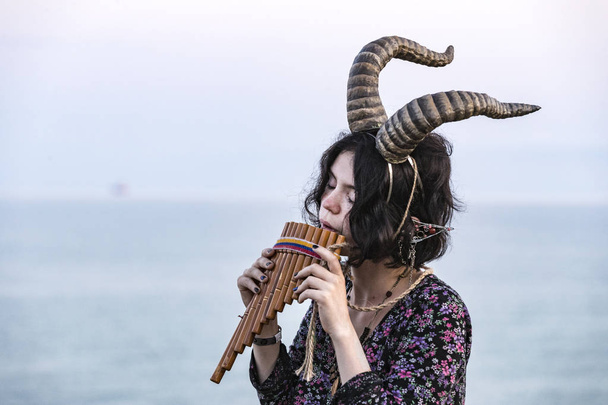 Girl with horns of a mountain goat on a background of the sea. - Photo, Image