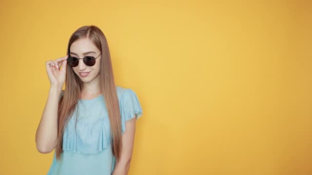 meisje brunette in blauw t-shirt over geïsoleerde oranje achtergrond toont emoties - Video