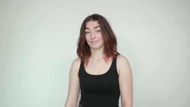 beautiful girl in black tank top over isolated white background shows emotions - Footage, Video