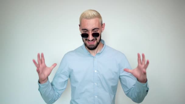 Mann mit blonden Haaren, schwarzem Bart vor weißem Hintergrund zeigt Emotionen - Filmmaterial, Video