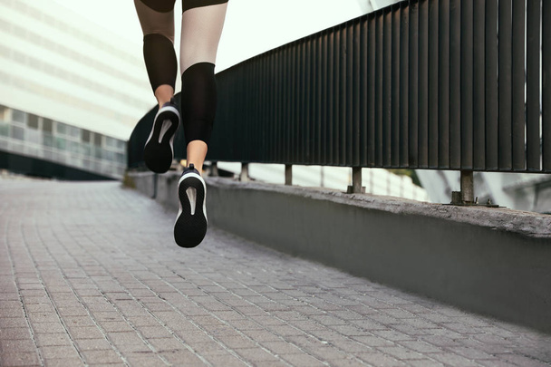 Beautiful sporty young woman running on street, closeup - Foto, Imagen