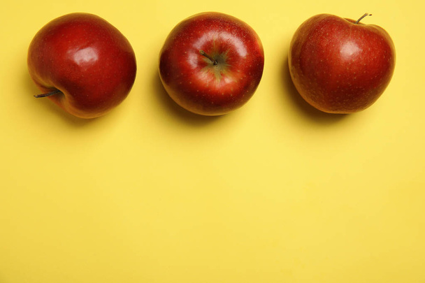 Flat lay composition with ripe juicy red apples on yellow background, space for text - Fotoğraf, Görsel