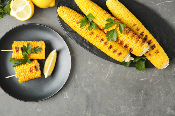 Flat lay composition of grilled corn cobs on grey table - Foto, Imagem