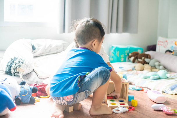 Asiatico carino piccoli bambini giocare con giocattolo scatola mentre seduta su
 - Foto, immagini