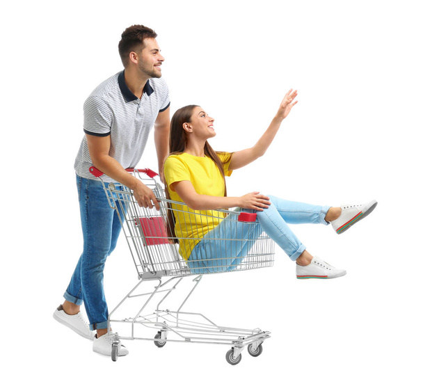 Young couple with shopping cart on white background - Fotoğraf, Görsel
