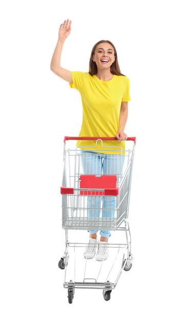 Young woman with empty shopping cart on white background - Fotó, kép