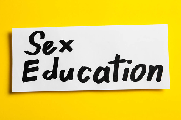 Piece of paper with phrase "SEX EDUCATION" on yellow background, top view - Photo, Image