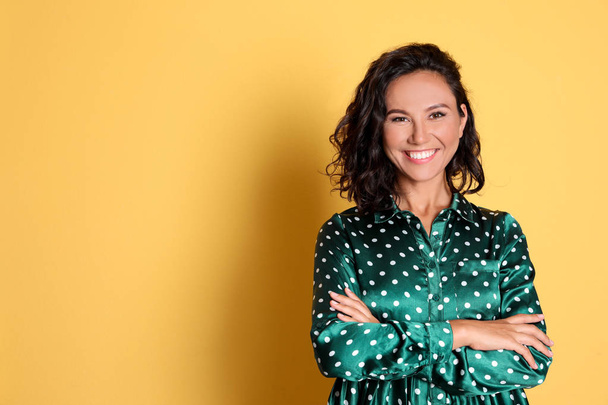 Happy young woman with crossed hands on yellow background. Space for text - Foto, Bild