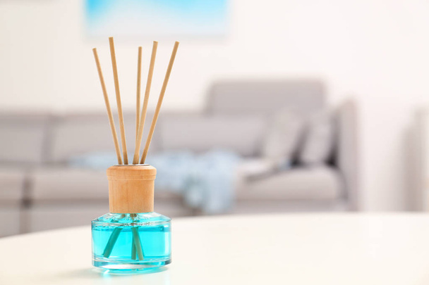Reed air freshener with essential oil on table in room. Space for text - Фото, изображение