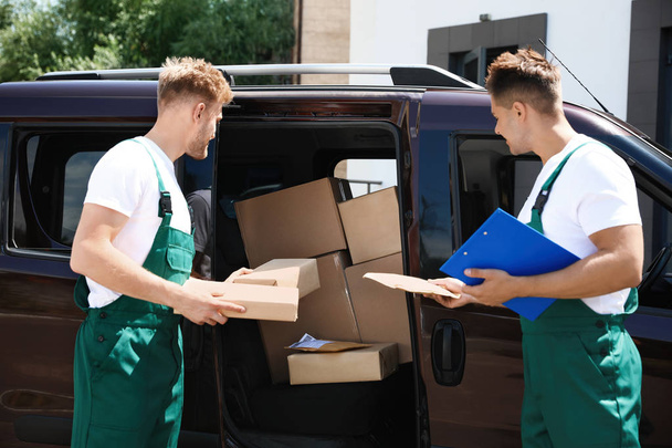 Young couriers with parcels near delivery car outdoors - Photo, image
