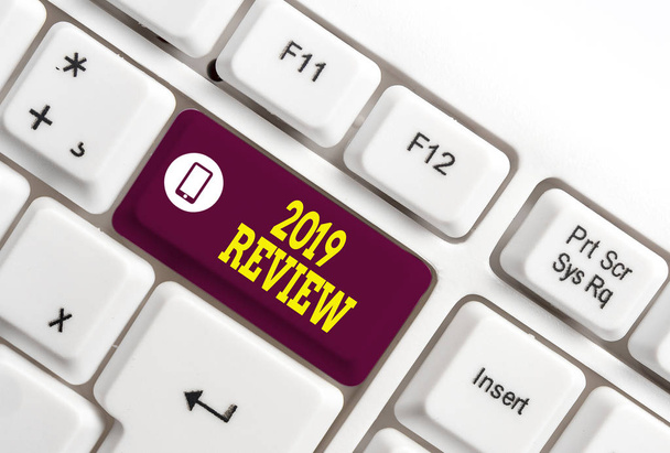 Writing note showing 2019 Review. Business photo showcasing New trends and prospects in tourism or services for 2019 White pc keyboard with note paper above the white background. - Photo, Image
