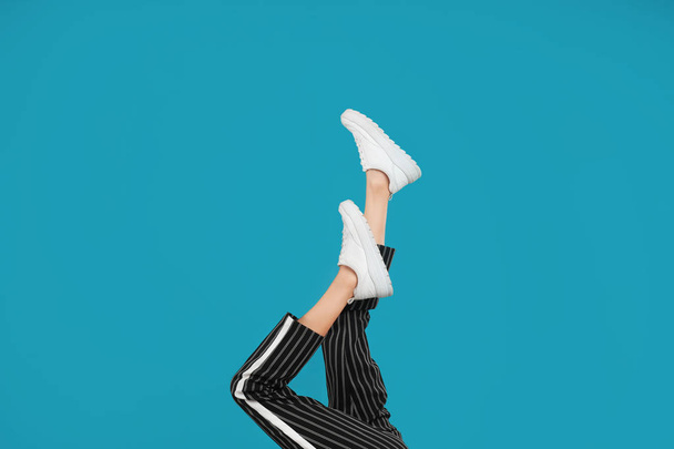 Woman in stylish sport shoes on light blue background - Фото, изображение