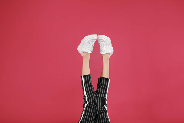 Woman in stylish sport shoes on crimson background - Valokuva, kuva