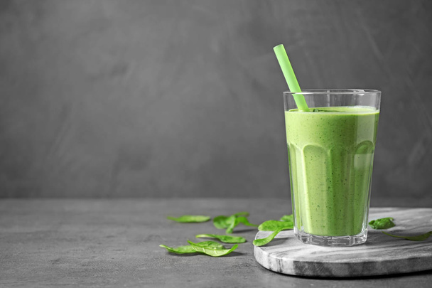 Glass of healthy green smoothie with fresh spinach on grey table, space for text - Foto, Imagem