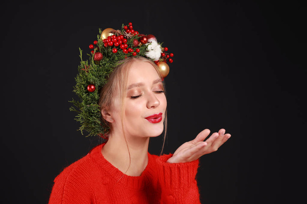 Beautiful young woman wearing Christmas wreath on black background - Photo, image