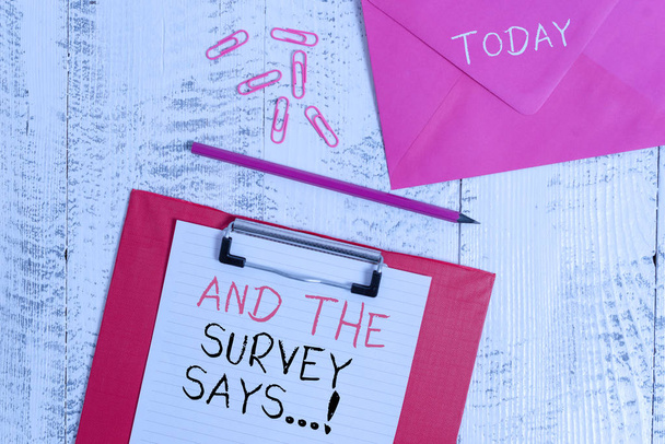 Conceptual hand writing showing And The Survey Says. Business photo showcasing written spoken results of short quiz or exam on internet Colored clipboard paper sheet pencil clips wooden background. - Photo, Image