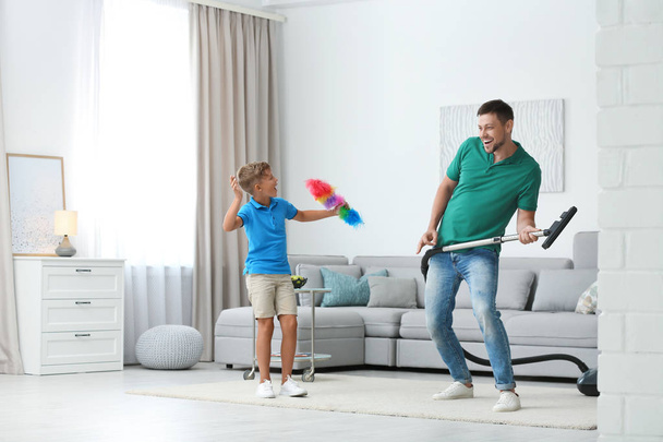 Dad and son having fun while cleaning living room together - Foto, immagini