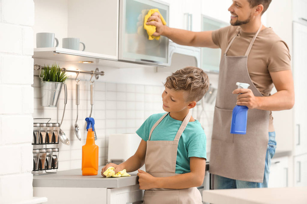 Dad and son cleaning in kitchen together - Fotó, kép