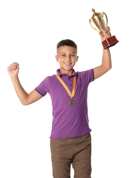 Happy boy with golden winning cup and medal on white background - Foto, imagen