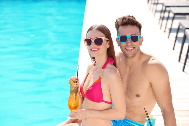 Happy young couple with cocktails near swimming pool - Φωτογραφία, εικόνα
