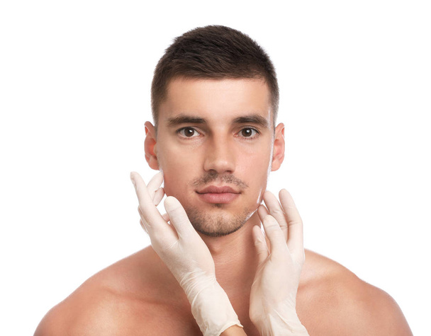 Doctor examining man's face for cosmetic surgery on white background - Фото, изображение