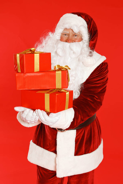 Authentic Santa Claus with gift boxes on red background - Photo, Image