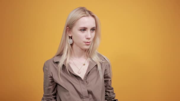 Blondes Mädchen in brauner Bluse über orangefarbenem Hintergrund zeigt Emotionen - Filmmaterial, Video