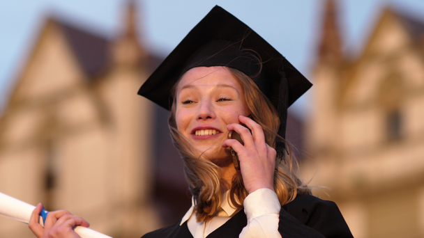 Šťastná hezká dívka absolvent v šatech mluvit na mobilním telefonu. - Záběry, video