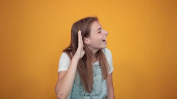 Jonge vrouw draagt wit t-shirt, over oranje achtergrond toont emoties - Video