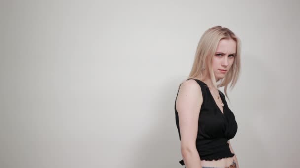 szőke lány egy fekete ruhában át elszigetelt fehér háttér mutatja érzelmek - Felvétel, videó
