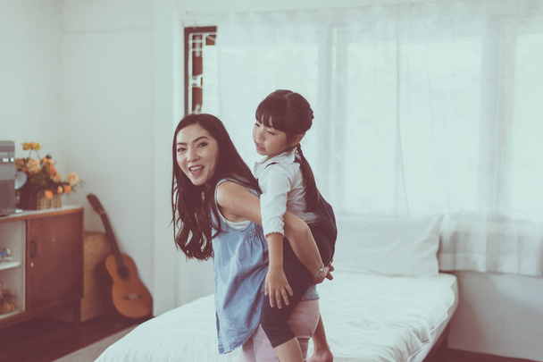 Single asian mom and daughter on a piggy back ride,Happy funny and smiling - Фото, зображення
