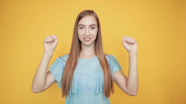 girl brunette in blue t-shirt over isolated orange background shows emotions - Materiał filmowy, wideo