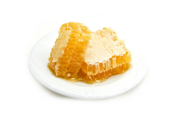 Свежий мед / Close up of yellow sweet honeycomb slice white pla
 - Фото, изображение