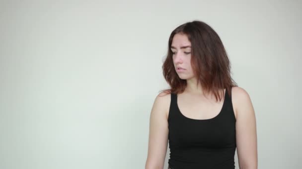 krásná dívka v černém tanku nad izolovaným bílým pozadím vykazuje emoce - Záběry, video