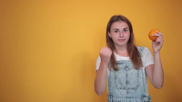 junge Frau trägt weißes T-Shirt, über orangefarbenem Hintergrund zeigt Emotionen - Filmmaterial, Video