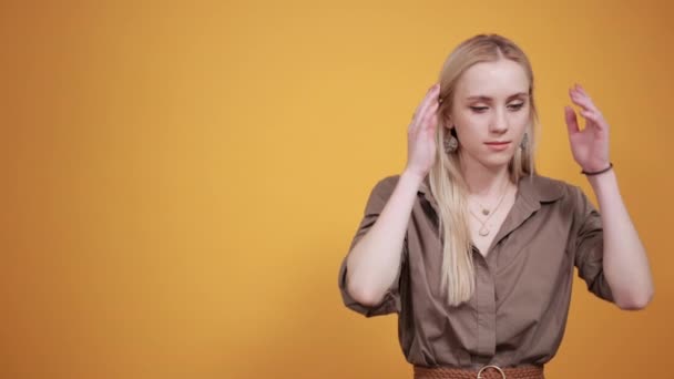 szőke lány barna blúz át elszigetelt narancssárga háttér mutatja érzelmek - Felvétel, videó