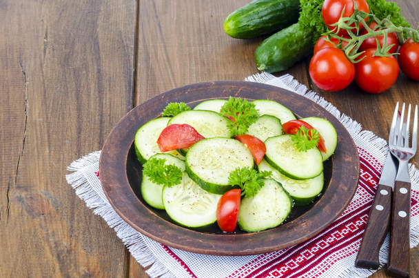 Diät-Salat aus frischen Gurken und Tomaten, in Scheiben geschnitten auf Holztisch - Foto, Bild