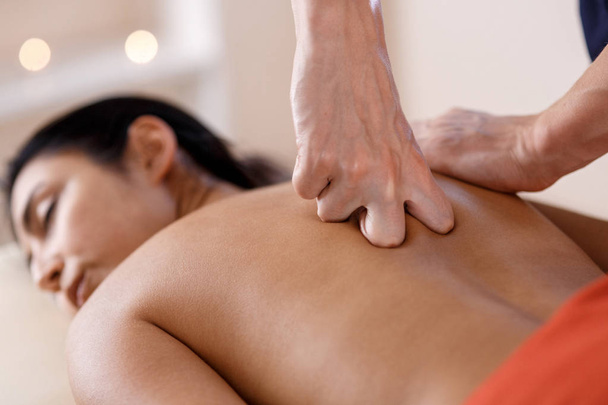 A young woman gets a massage procedure. Masseur makes back massage. - Zdjęcie, obraz