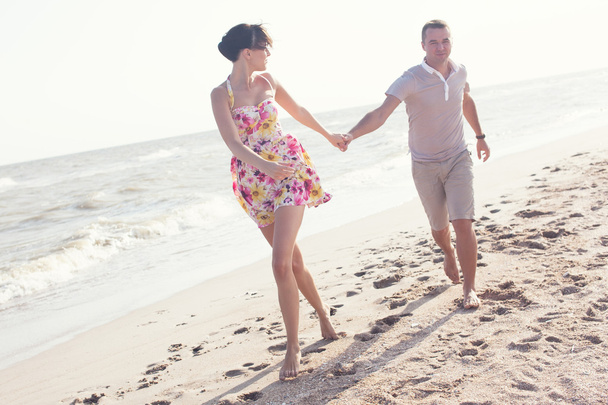 Dynamic picture of running couple on the beach. Holding hands. Summertime fun - Photo, Image