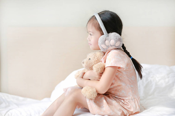 Adorable little Asian child girl wearing winter earmuffs and hug - Valokuva, kuva