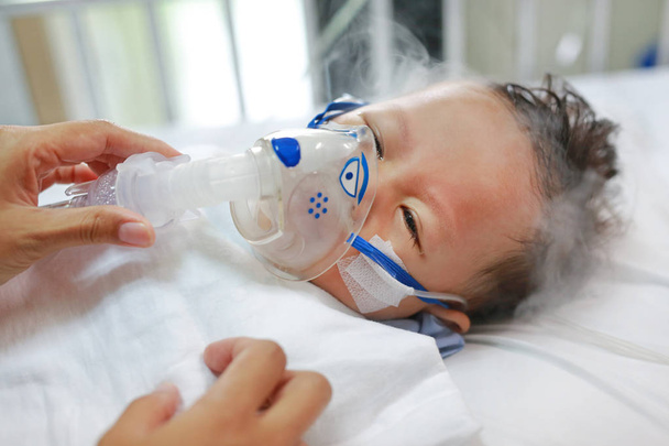 Baby has asthma and need nebulizations, Sick boy inhalation therapy by the mask of inhaler. Baby boy has a nasal congestion. Baby boy making inhalation with nebulizer. - Foto, afbeelding