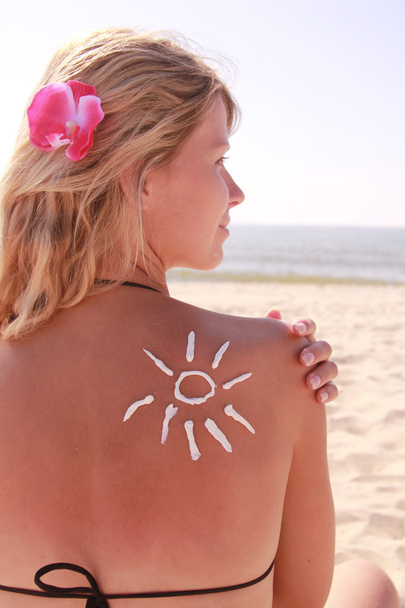 crema solar en la espalda femenina en la playa
 - Foto, Imagen